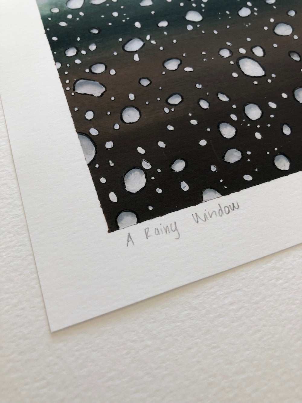 Art print of raindrops on a window with 'A Rainy Window' text written on it in pencil