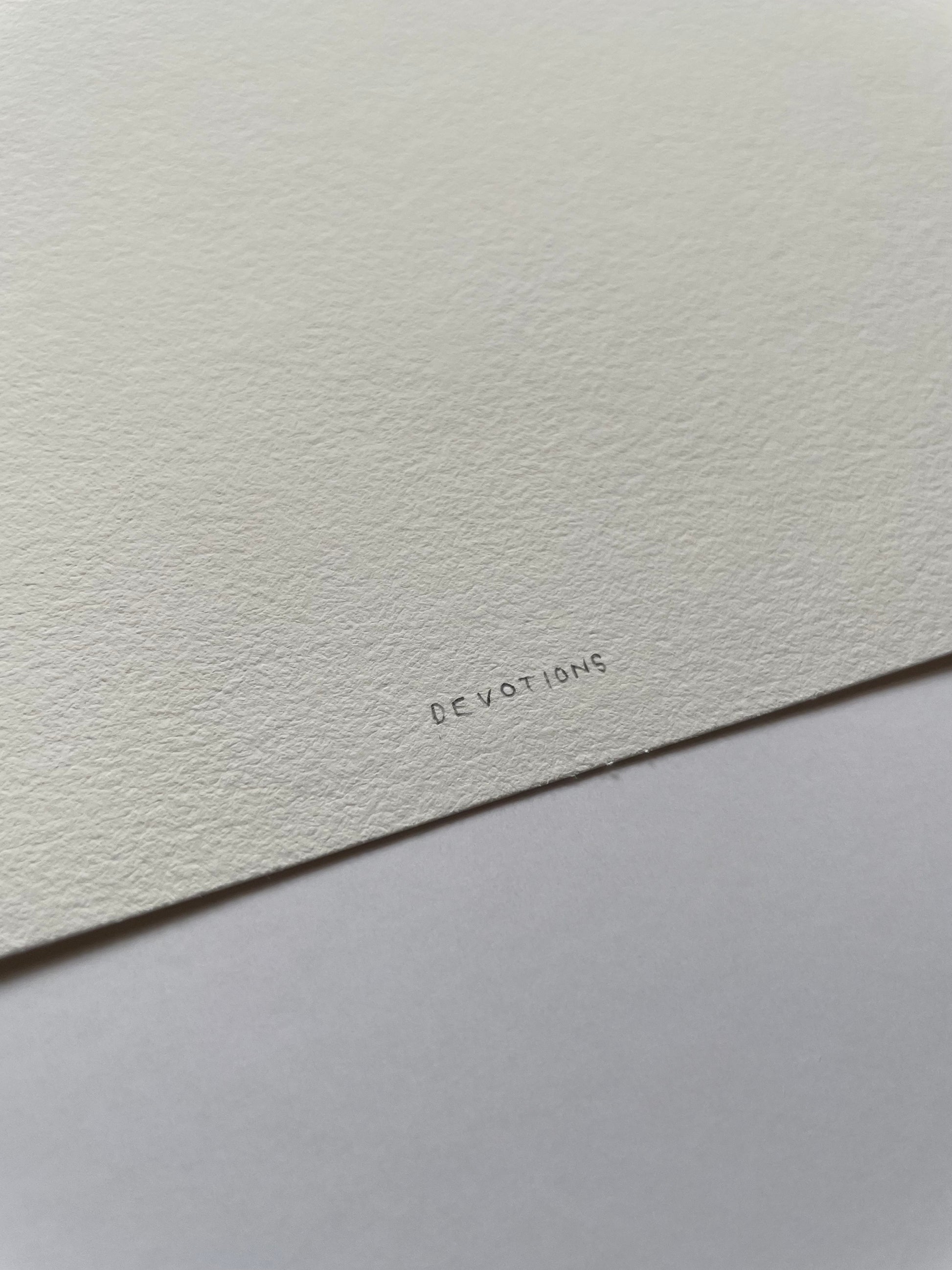 Close-up of a light textured paper with 'DEVOTIONS' written on it.