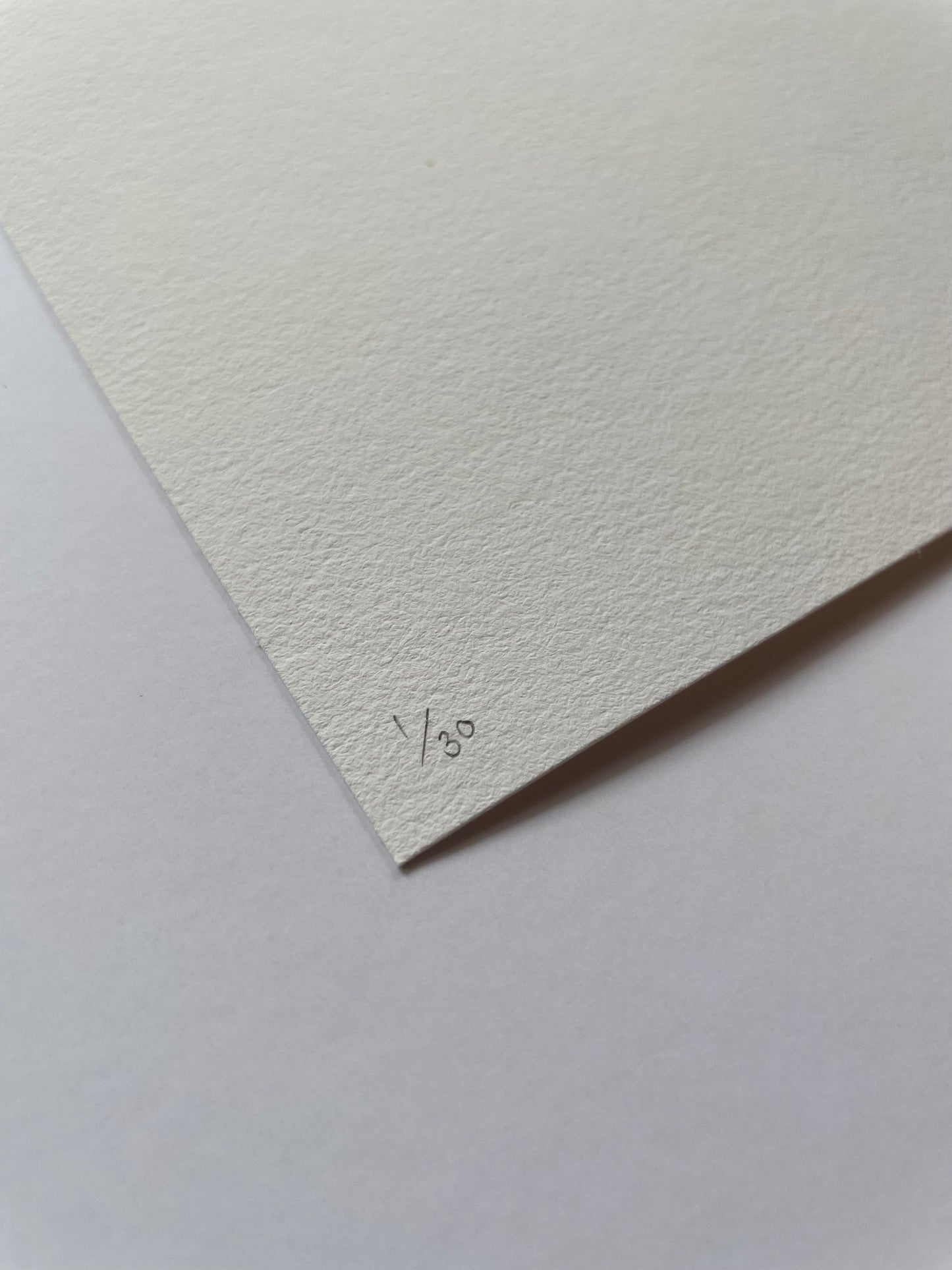 Corner of a textured light paper with '1/30' written on it, on a matching light background.