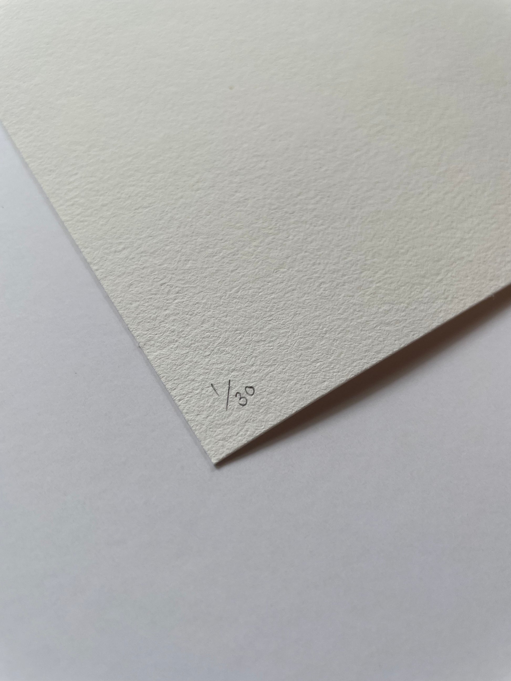 Corner of a textured light paper with '1/30' written on it, on a matching light background.