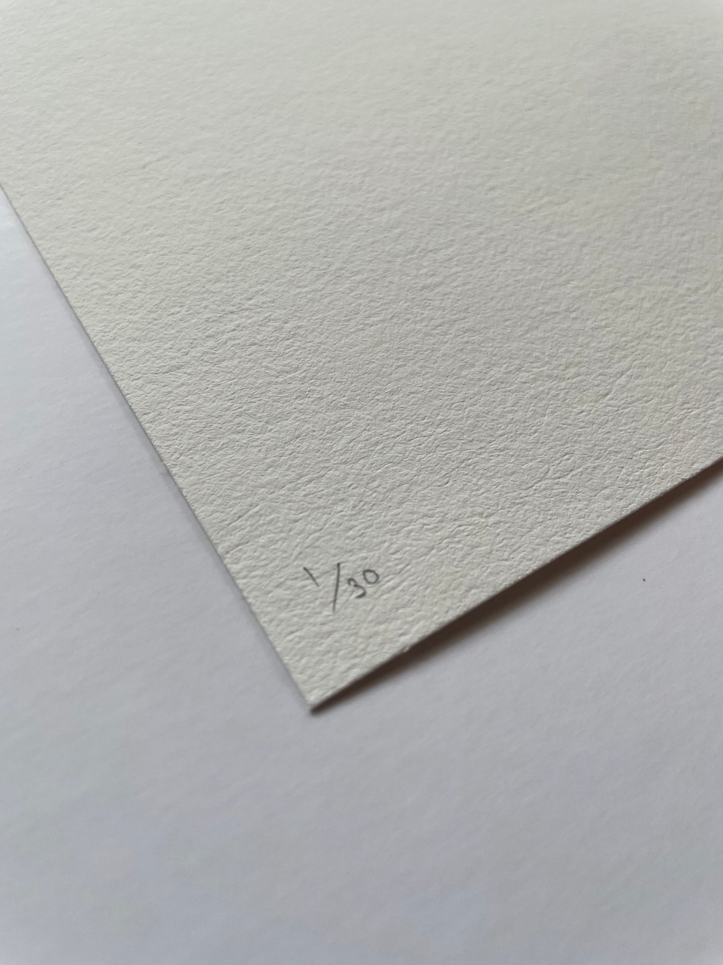 Corner of textured white paper with '1/30' written on it, on a matching white background.