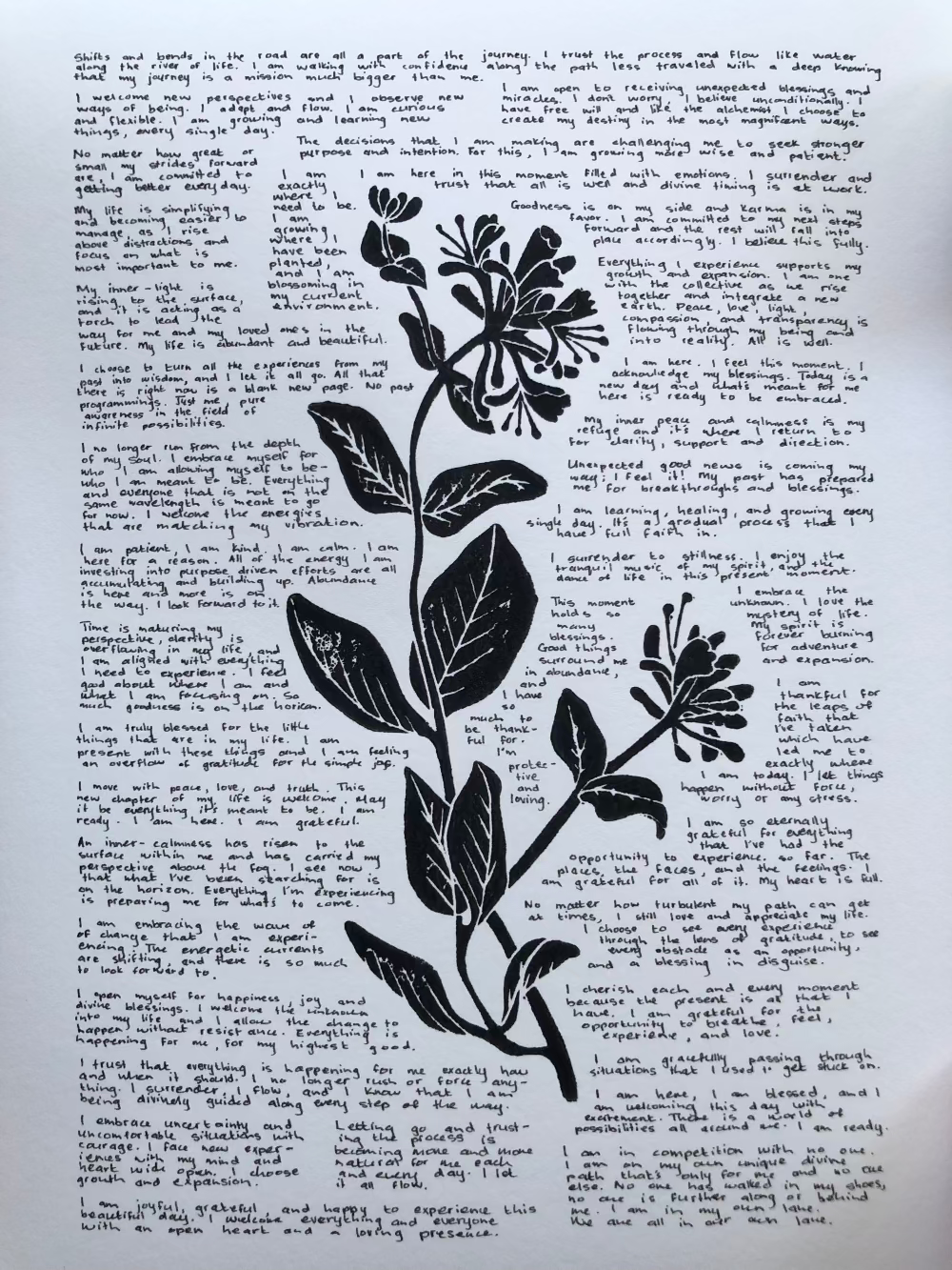 Lino print of a honeysuckle flower surrounded by tiny handwritten positive affirmations.