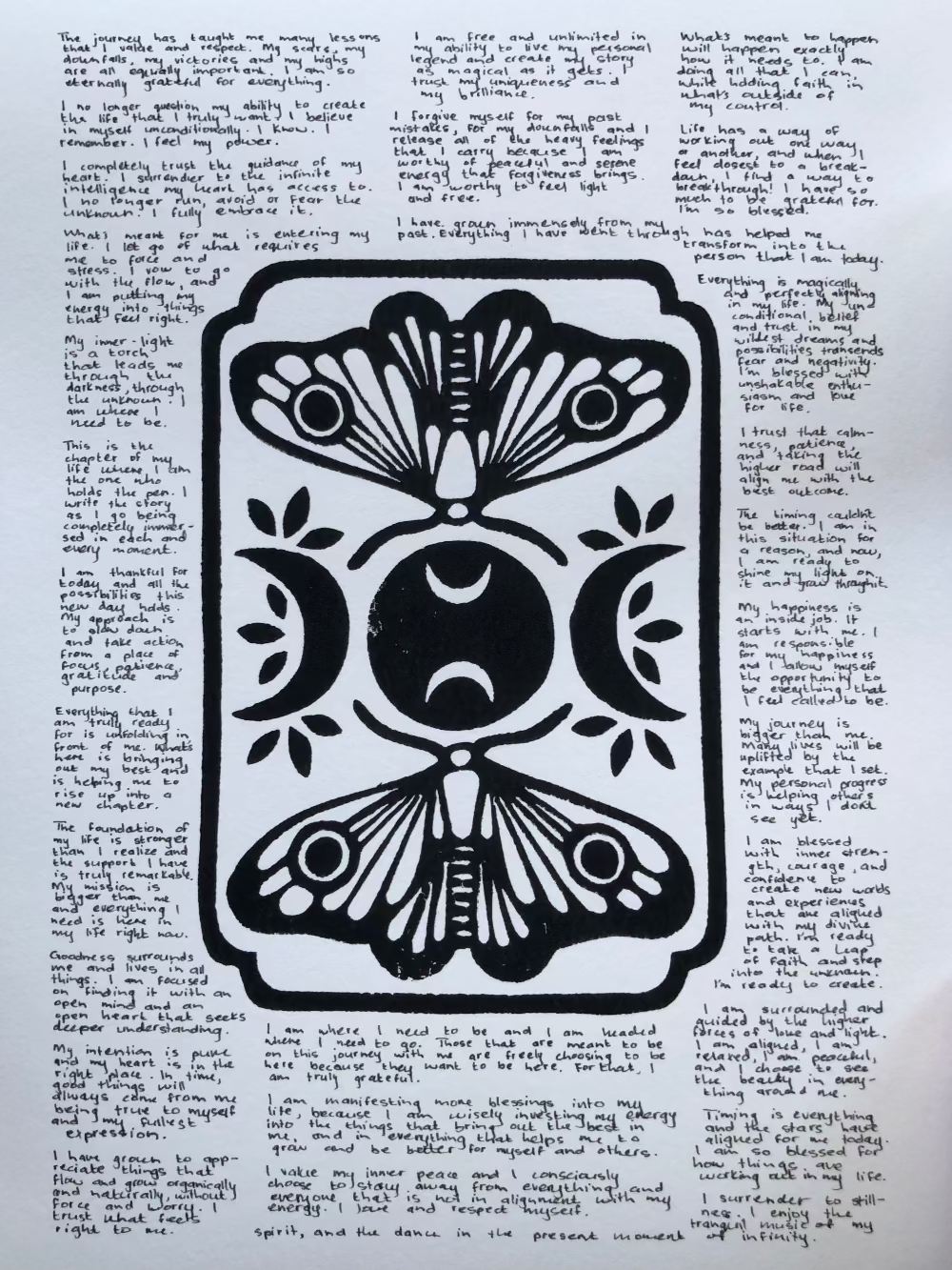 Lino print of moths and moons surrounded by tiny handwritten positive affirmations.