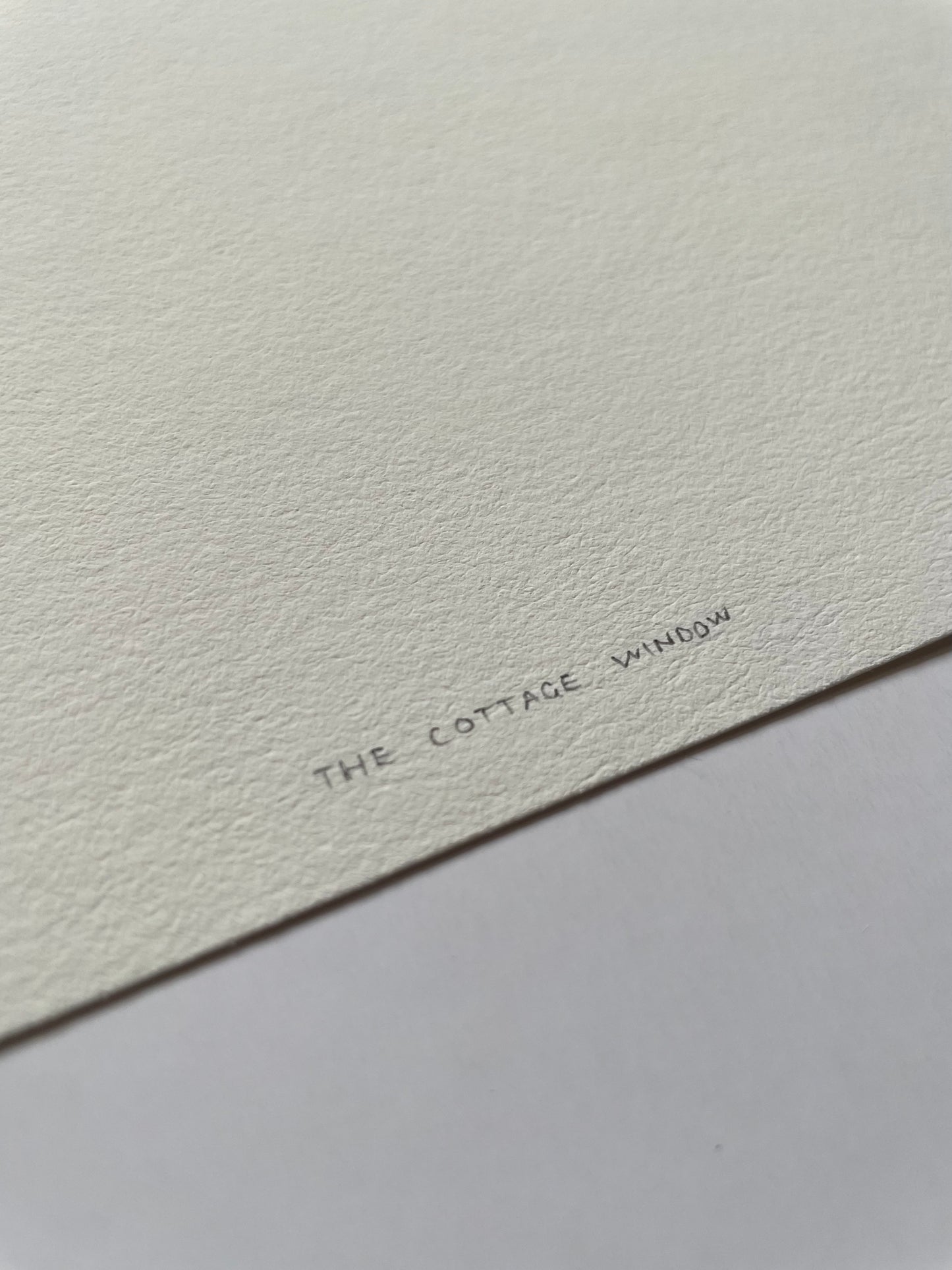 Text 'The Cottage Window' on a textured white background