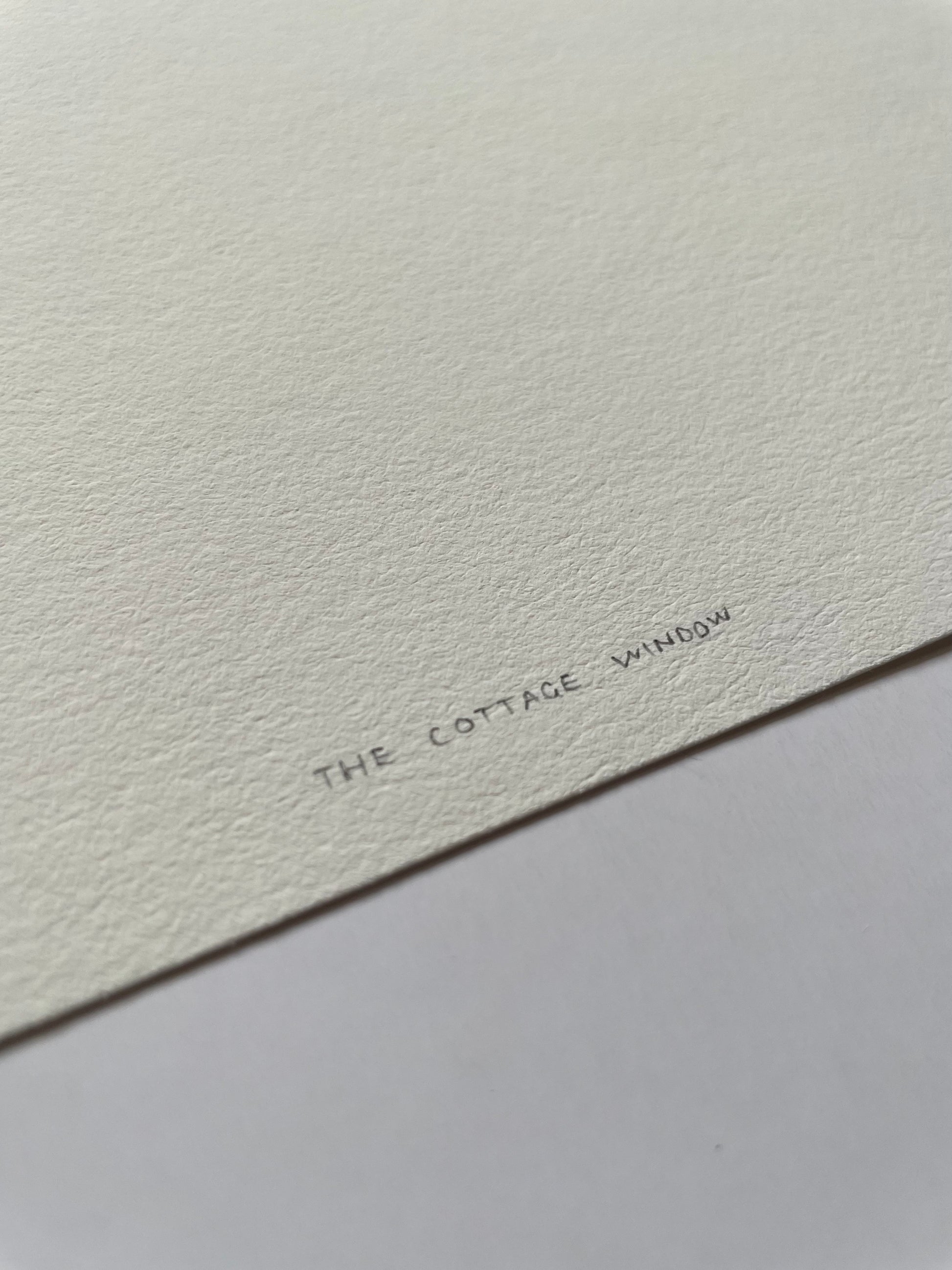 Text 'The Cottage Window' on a textured white background