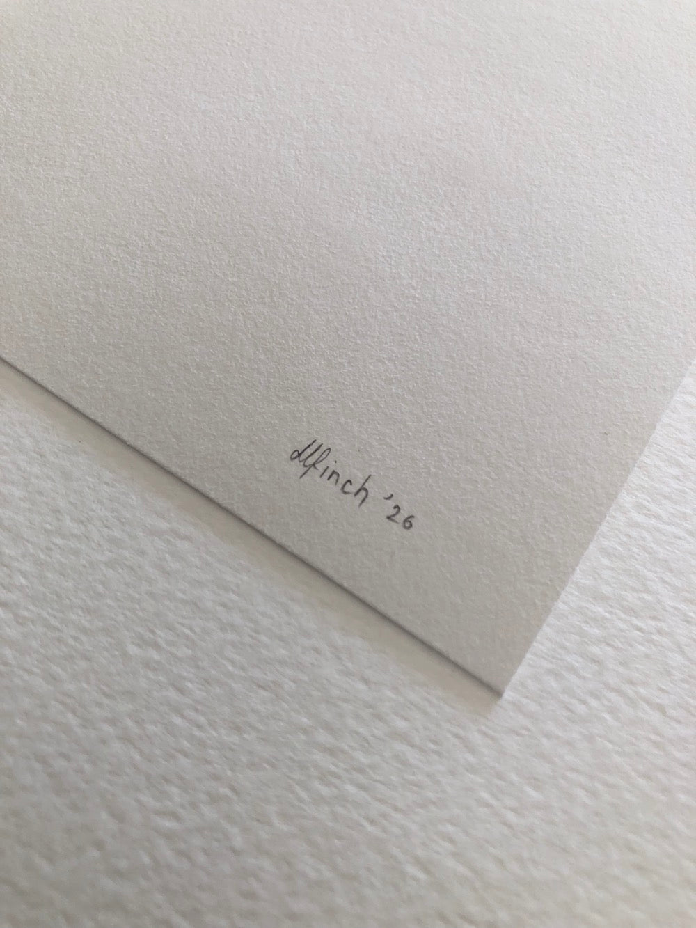 Close-up of textured paper with 'dlfinch '26' written on it in pencil