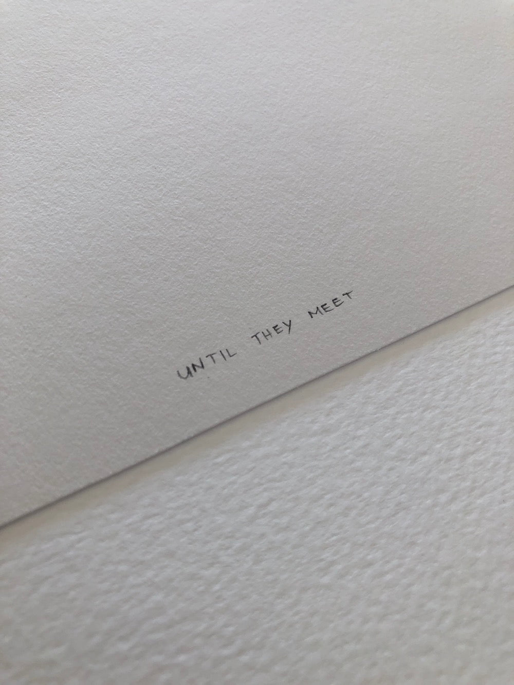 Text 'UNTIL THEY MEET' on textured white paper