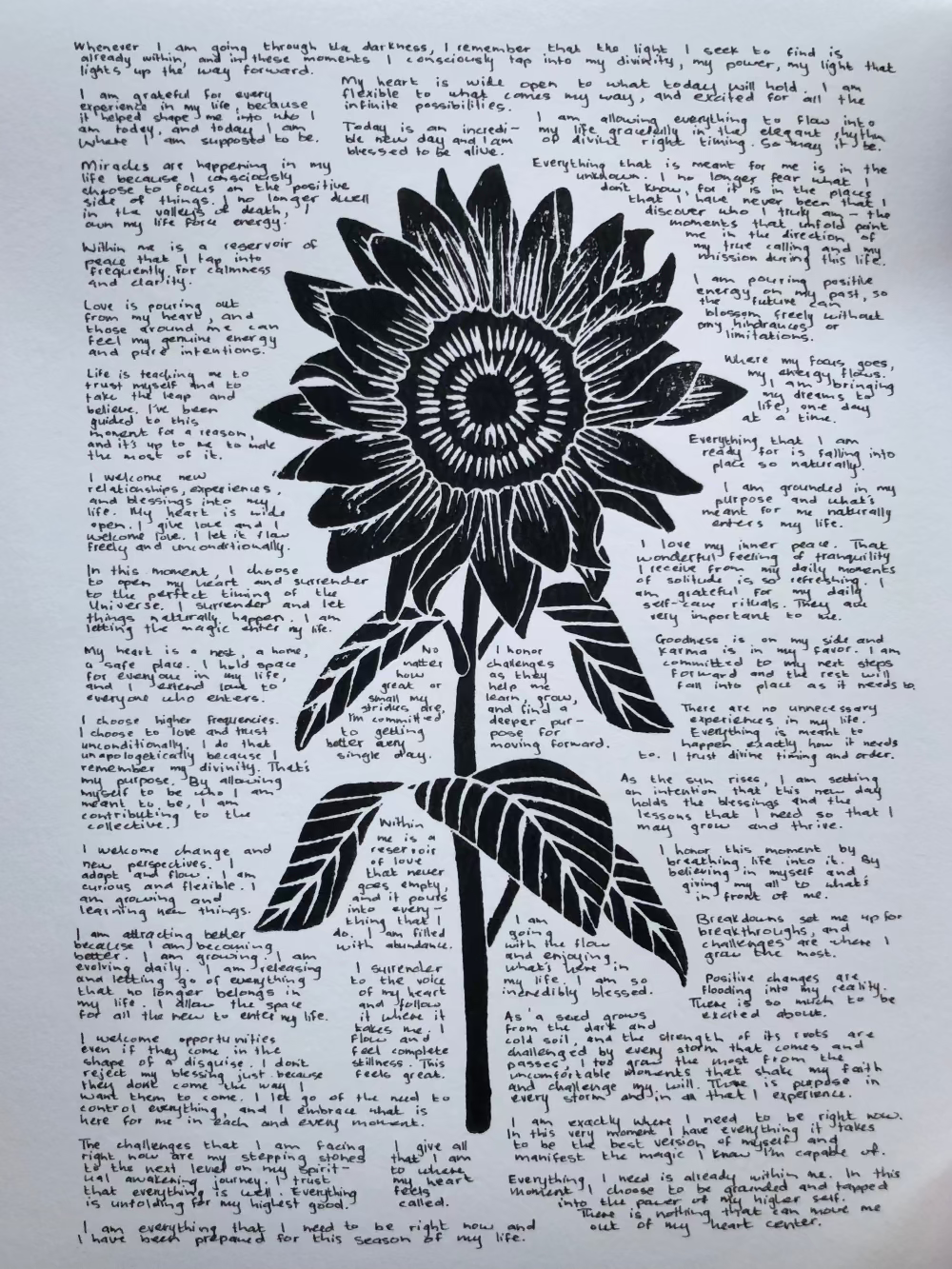 Lino print of a sunflower surrounded by tiny handwritten positive affirmations.