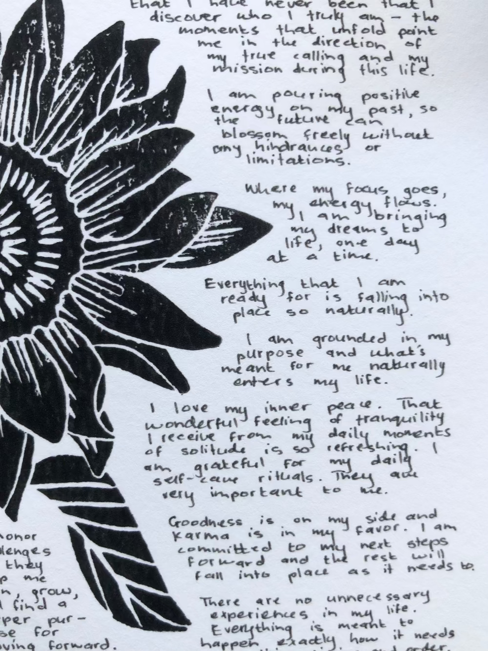 Close up of a lino print of a sunflower surrounded by tiny handwritten positive affirmations.