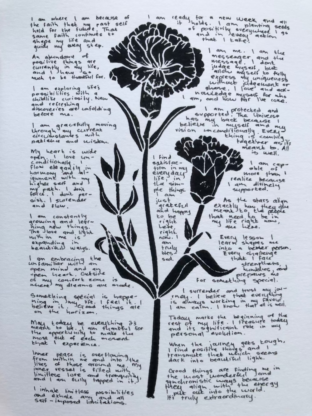 Lino print of a carnation flower surrounded by tiny handwritten positive affirmations.